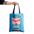 Blue Tote bag with pop art Campbell's Tomato Soup design held by a hand on a white background