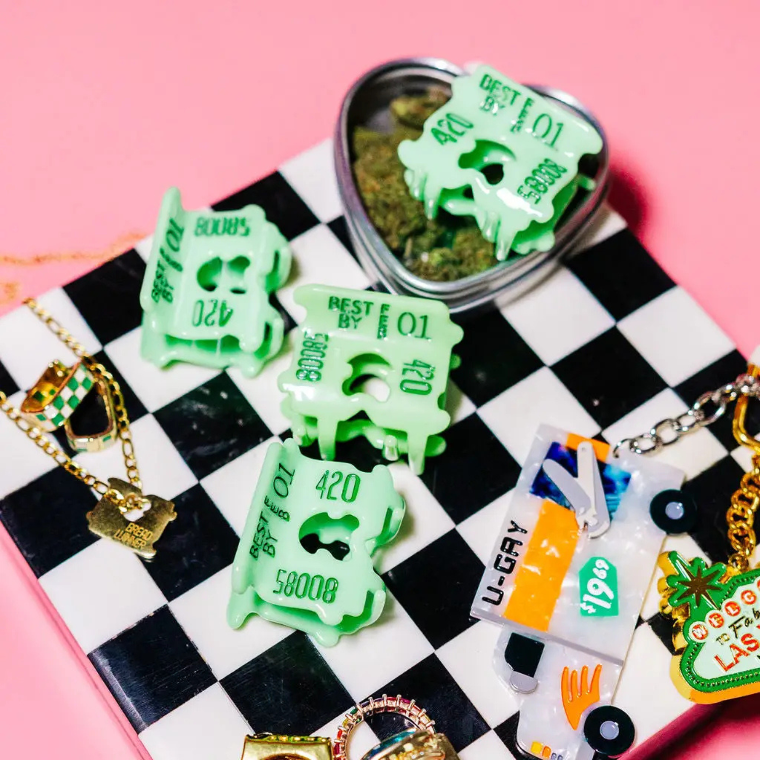 Green plastic hair claw clip that looks like a bread clip on a checkered surface with pink background