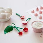 Cherry measuring spoons with sugar, eggs, and baking ingredients on a countertop, perfect for baking and cooking.