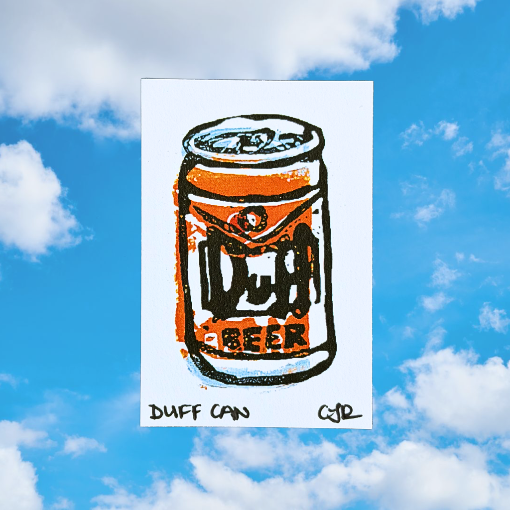 Linoleum carved print of a Duff Beer can with a blue sky and clouds in the background