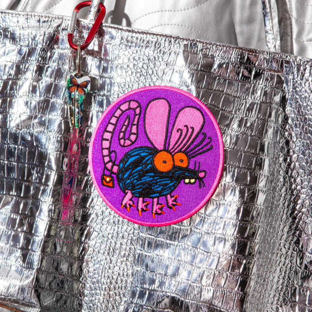 Silver reflective bag with a colorful patch featuring a cartoonish rat character on a purple circle.