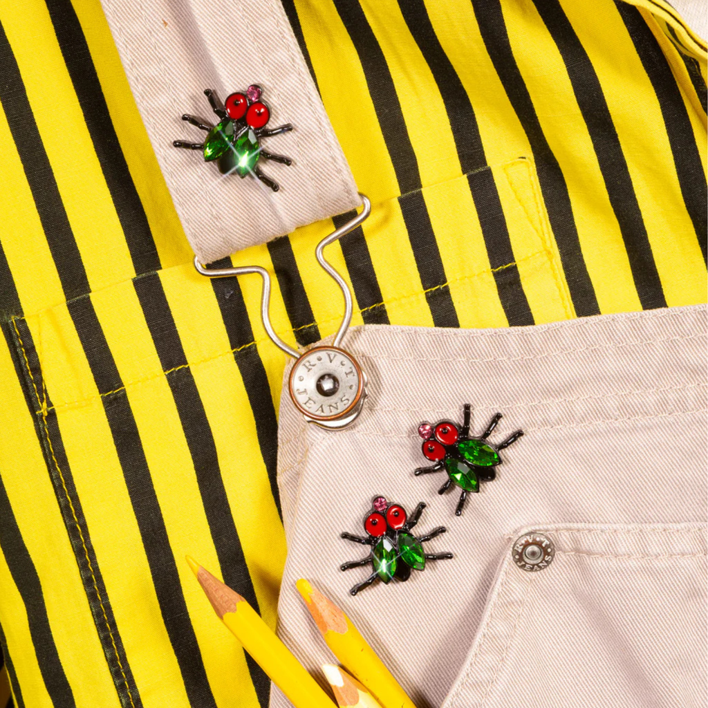 Close-up of a yellow shirt with black stripes and decorative fly brooches.