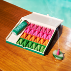 Colorful incense cones in a box with a lighter on a wooden surface by a pool.