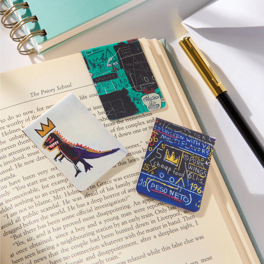 Colorful Baquiat design bookmarks on a book with a pen and notebook in the background
