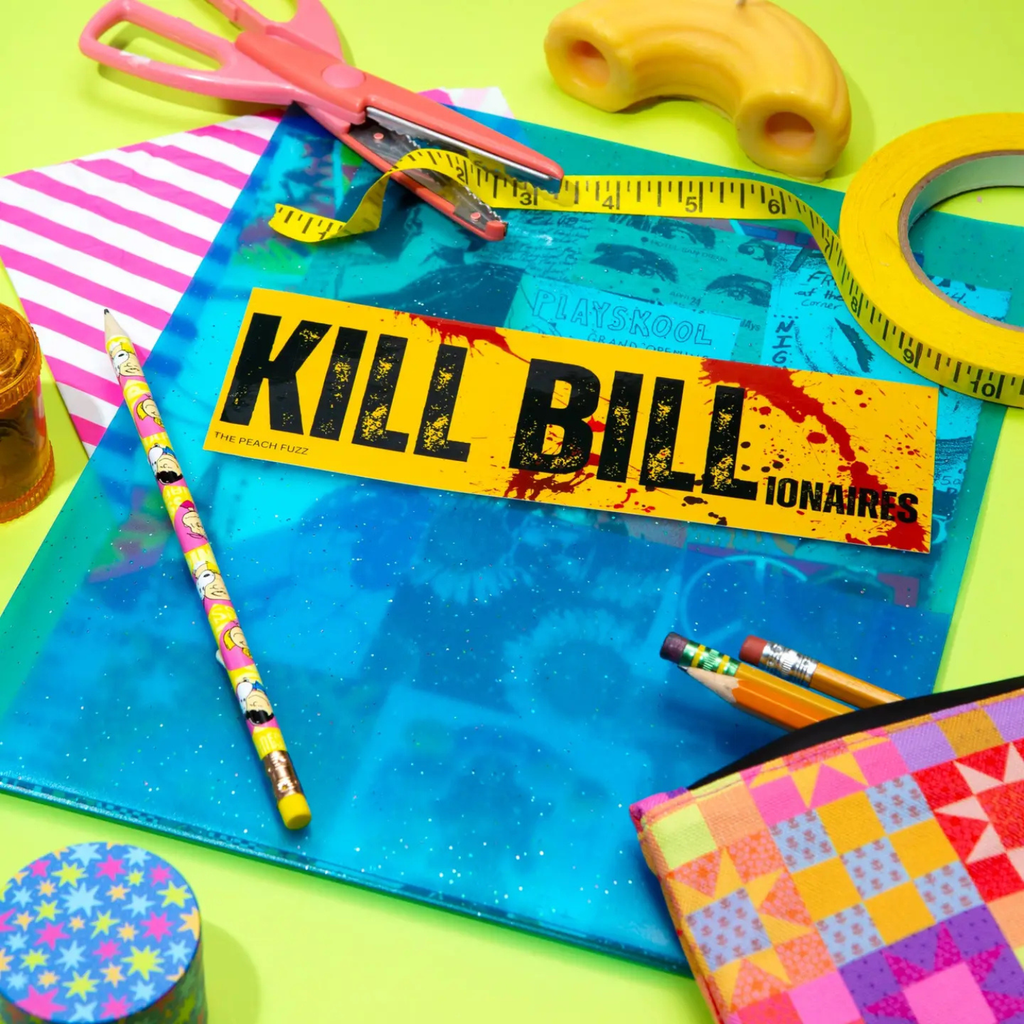Colorful stationery items including a 'Kill Bill' bumper sticker on a blue folder.