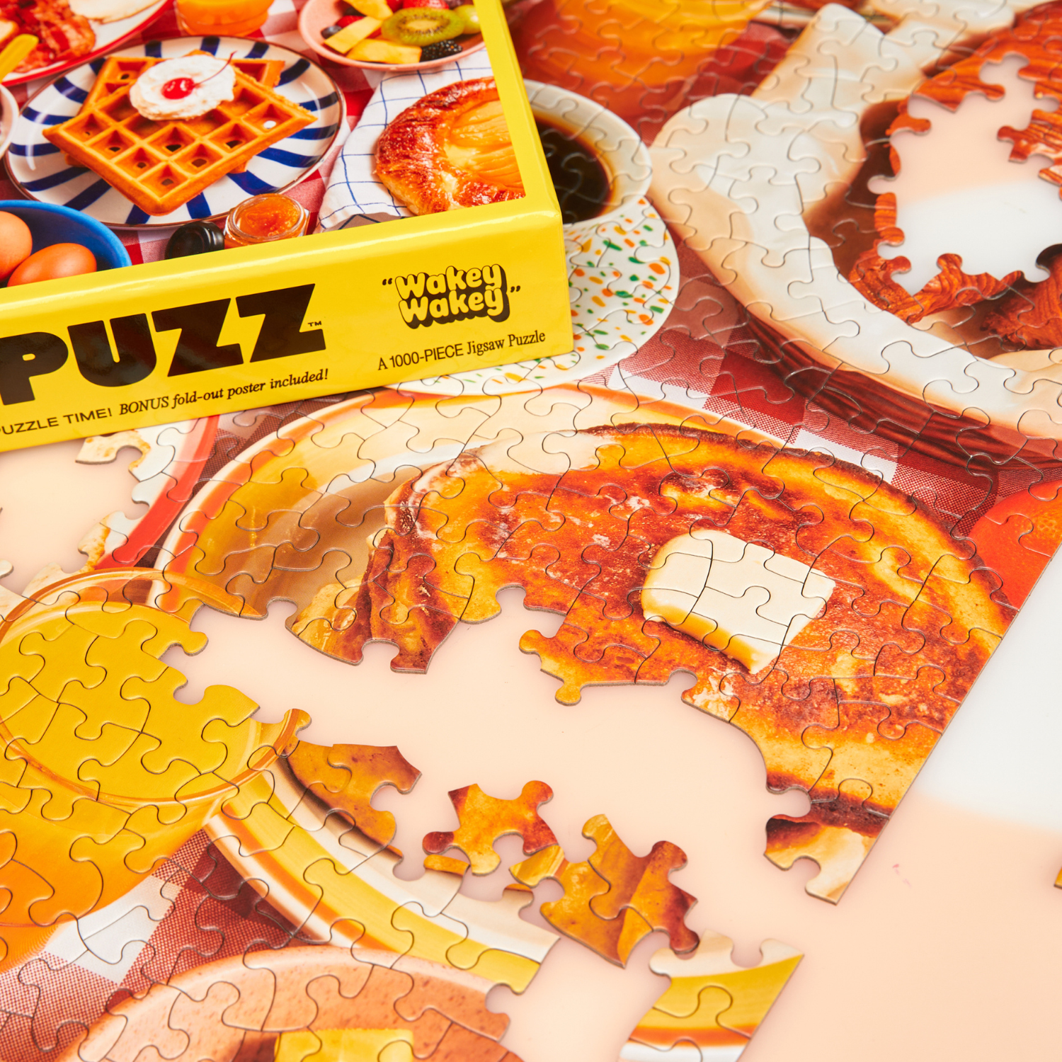Puzzle with a breakfast design, partially completed, next to a box labeled 'Wakey Wakey LE PUZZ'.