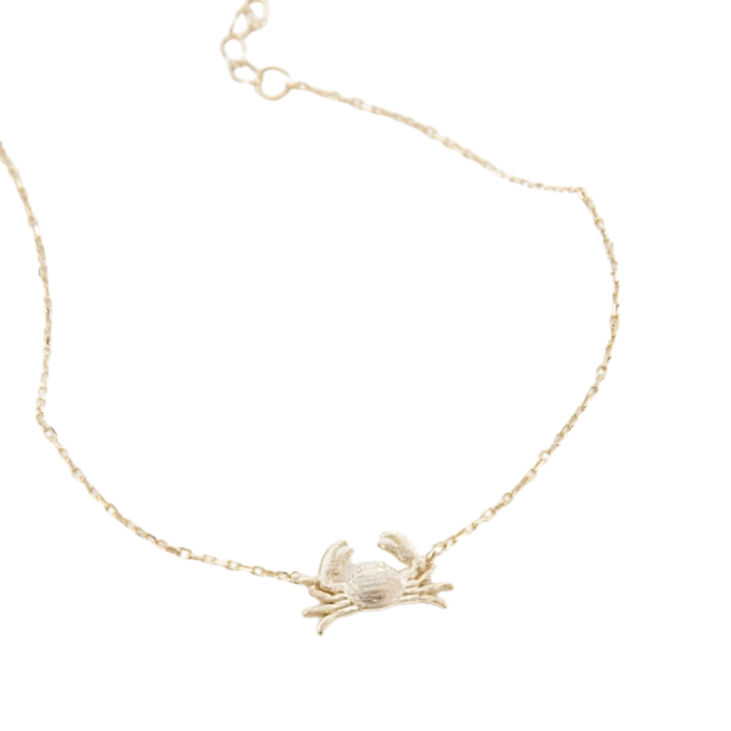 A delicate gold chain bracelet featuring a small, brushed textured gold crab pendant, displayed on a clean white background.