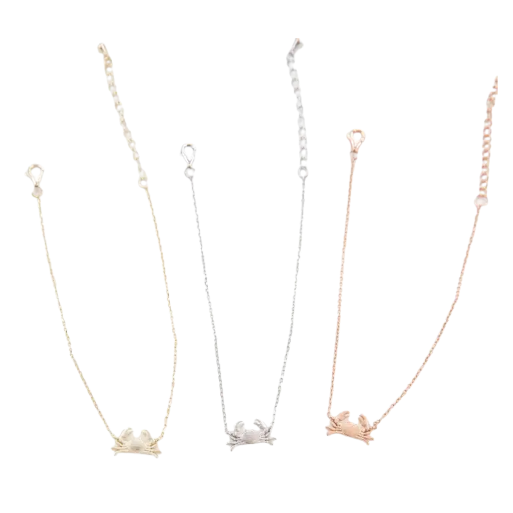 Three delicate chain bracelets with small Maryland blue crab pendants in gold, silver, and rose gold finishes, displayed against a plain white background.