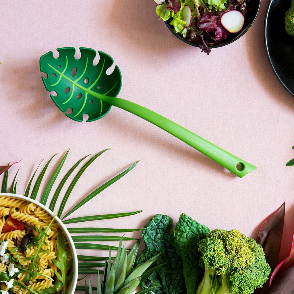 Monstera leaf ladle and serving spoon by OTOTO surrounded by fresh vegetables and salad ingredients, perfect for serving soups, pasta, and salads.