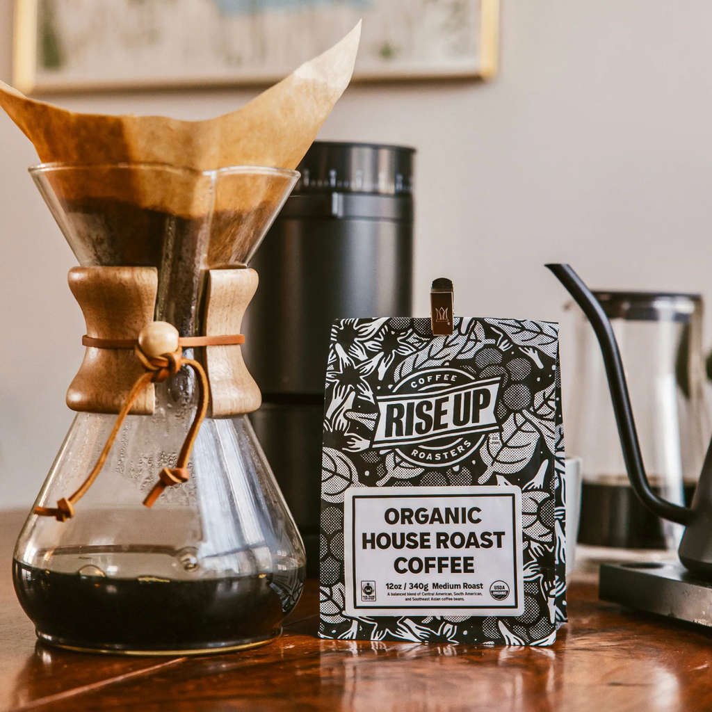 Coffee brewing setup with a Chemex, coffee bag labeled 'Rise Up Coffee', and a coffee press.