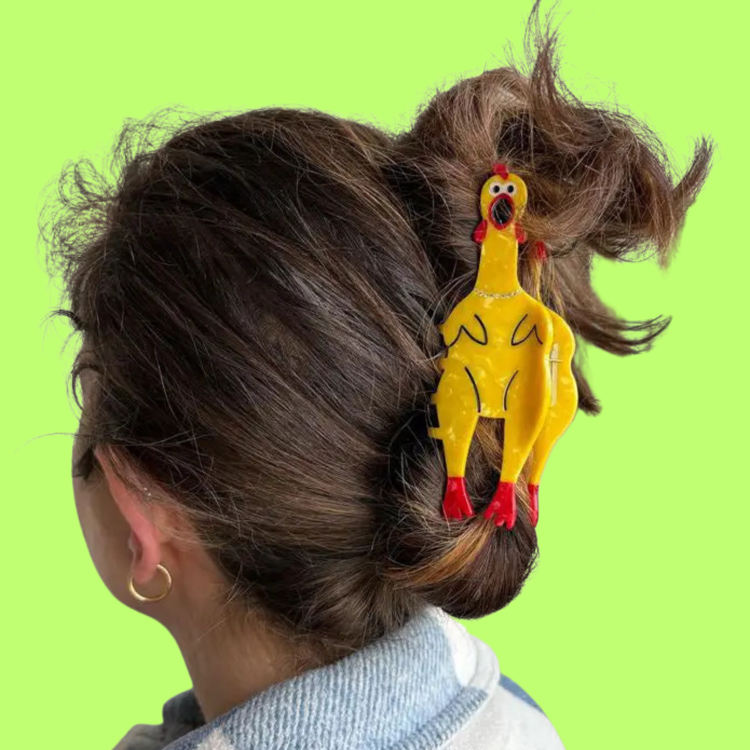 Person with a yellow chicken-shaped hair clip in their hair against a green background