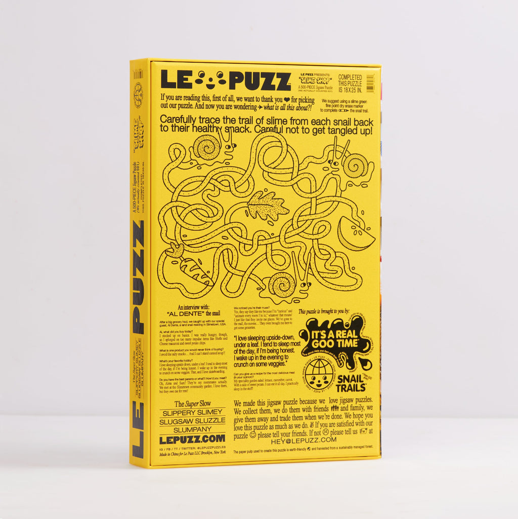 A yellow rectangular product box for 'LE PUZZ' shown upright against a light gray background. The front features a winding black line maze illustration with text instructions and promotional copy, including 'It's a real goo time!' and 'Snail Trails.