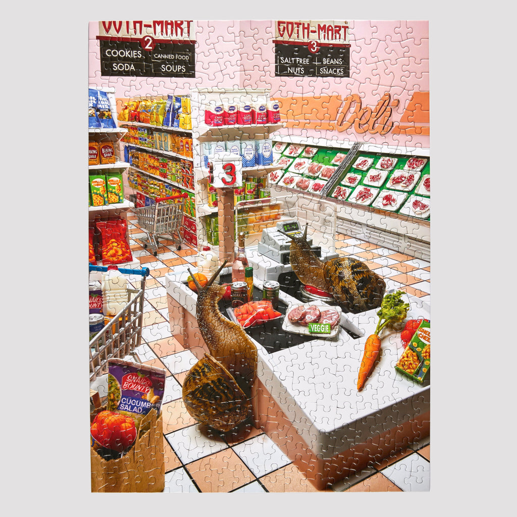 A completed jigsaw puzzle showing a detailed grocery store deli scene with shelves, produce, meat counter, and signage, photographed straight-on against a white background.