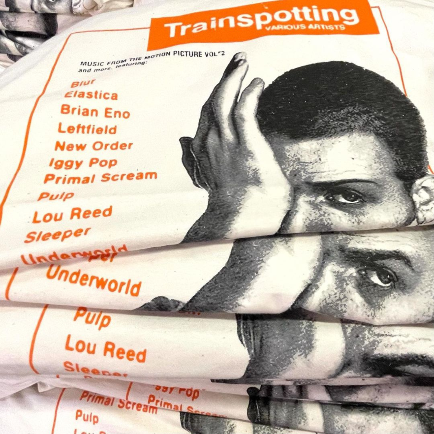 Shirt design of album cover for 'Trainspotting' soundtrack music from the motion picture, stacked in a pile.