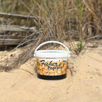 Bucket of Fisher's Popcorn on a sandy ground with grass in the background