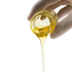 Hand with a glove holding a jar of honey with honey dripping.